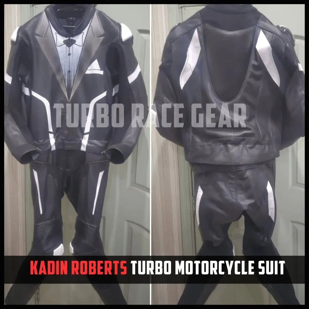 A black leather motorcycle racing suit with white graphic accents, shown in front and back views. The suit features a jacket with a lapel pin and matching pants.