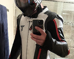 Person wearing a black and red jacket with a helmet, holding a phone.