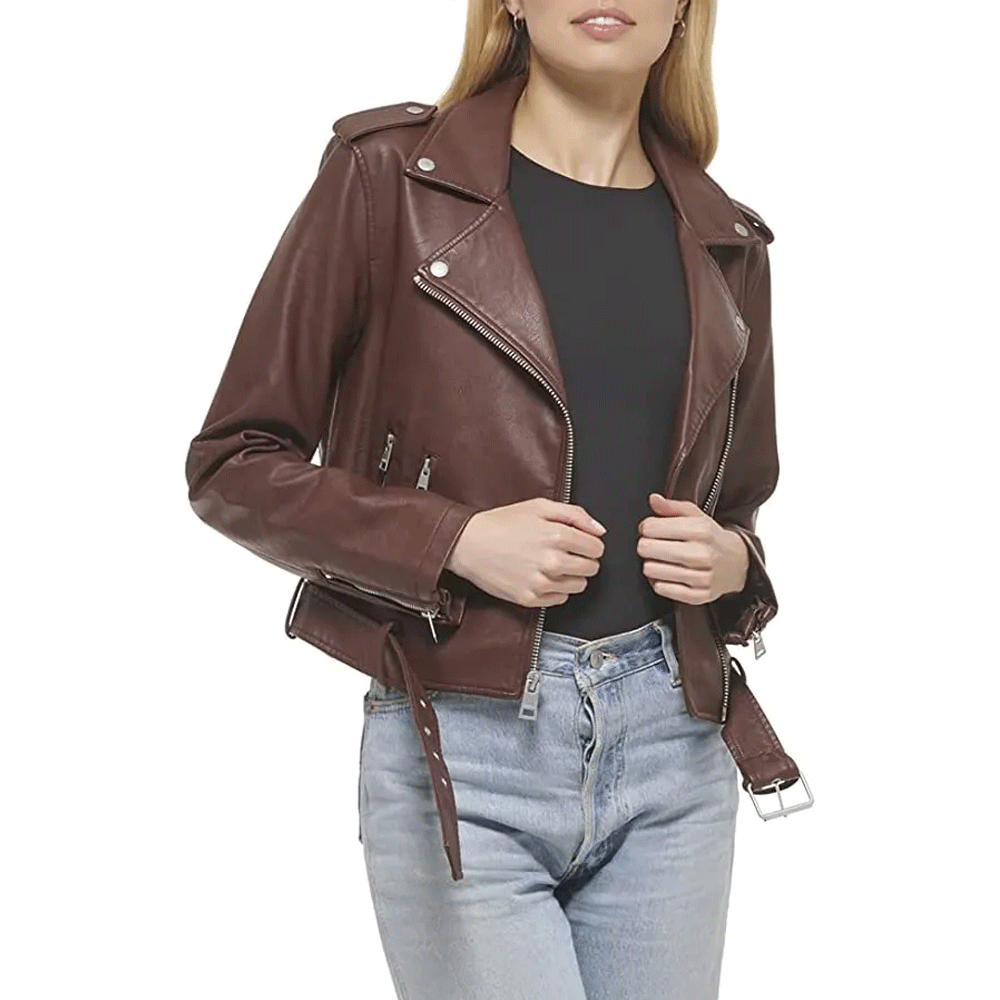 A woman wearing a brown leather motorcycle jacket with a mandarin collar and YKK zipper, paired with blue jeans.