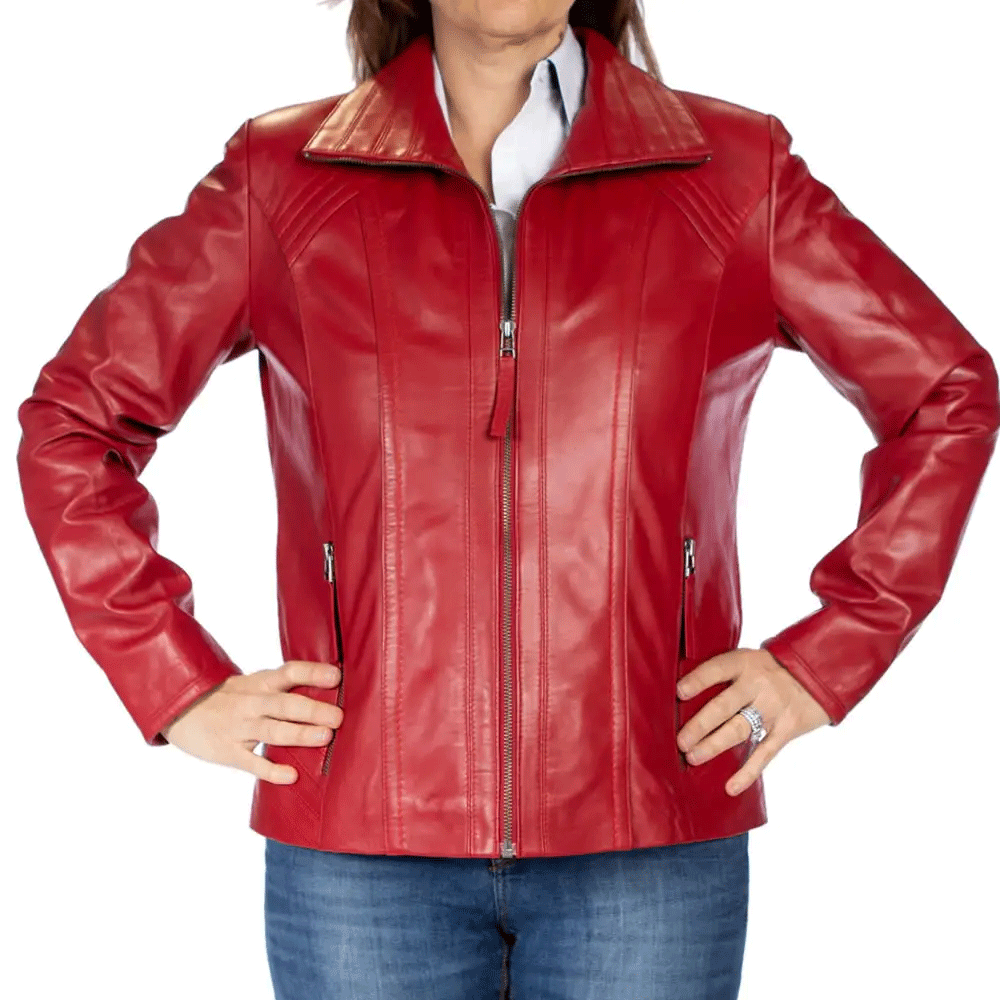 A woman facing forward, wearing a red leather motorcycle jacket with a mandarin collar and zipper details, paired with blue jeans.